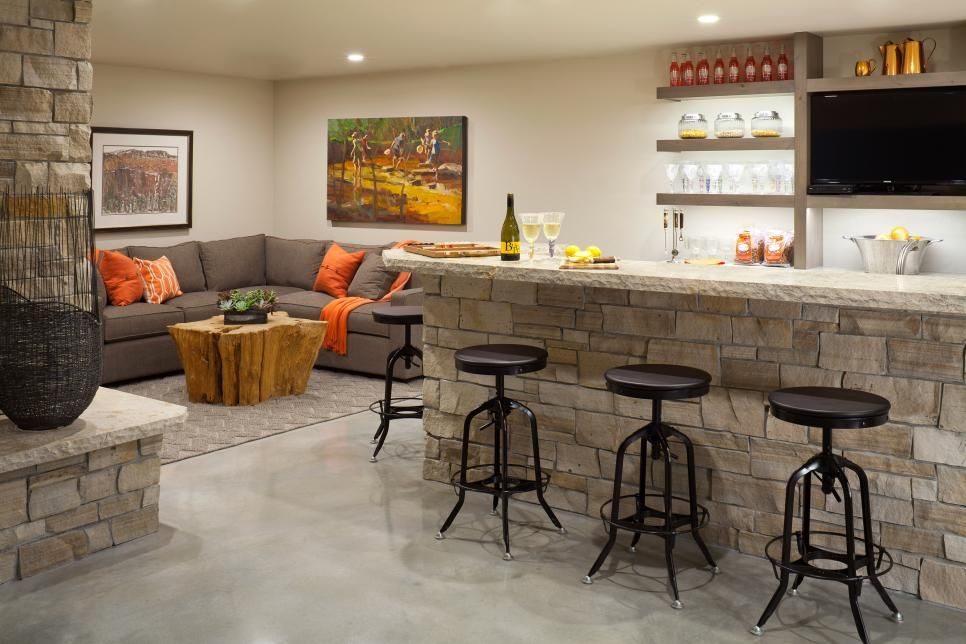 Basement bar and lounge with a stone-front bar, bar stools and an orange sectional