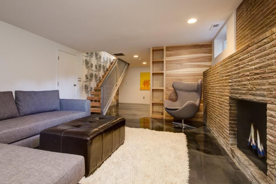 Basement living room with a stone fireplace, wood accent wall and a rounded egg chair